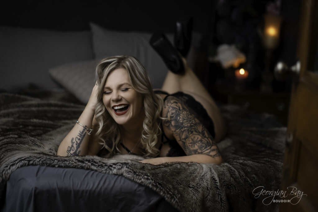 Beatuiful tattooed woman laughing on bed