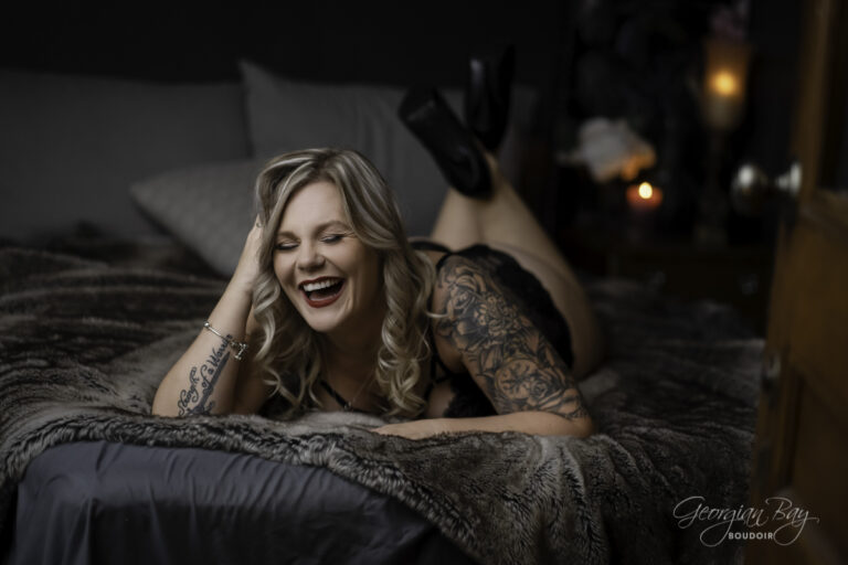 Beatuiful tattooed woman laughing on bed