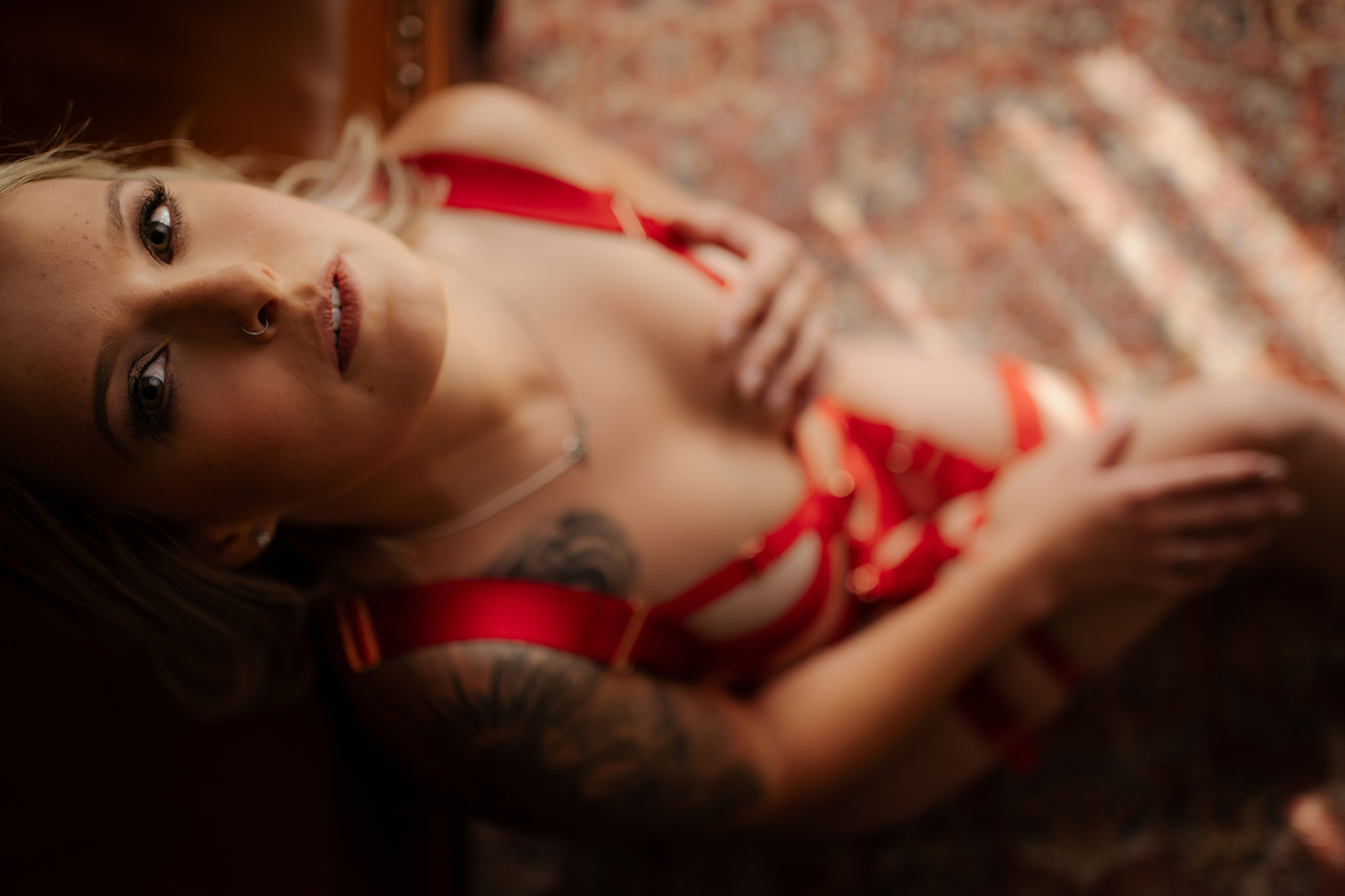 Blond woman in red strappy lingerie poses for boudoir photo shoot