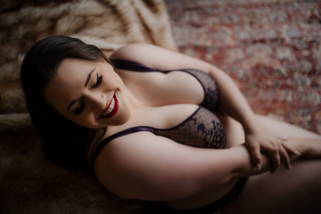 Overhead view of Curvy Woman in purple lingerie posing on leather chaise for her boudoir photo session