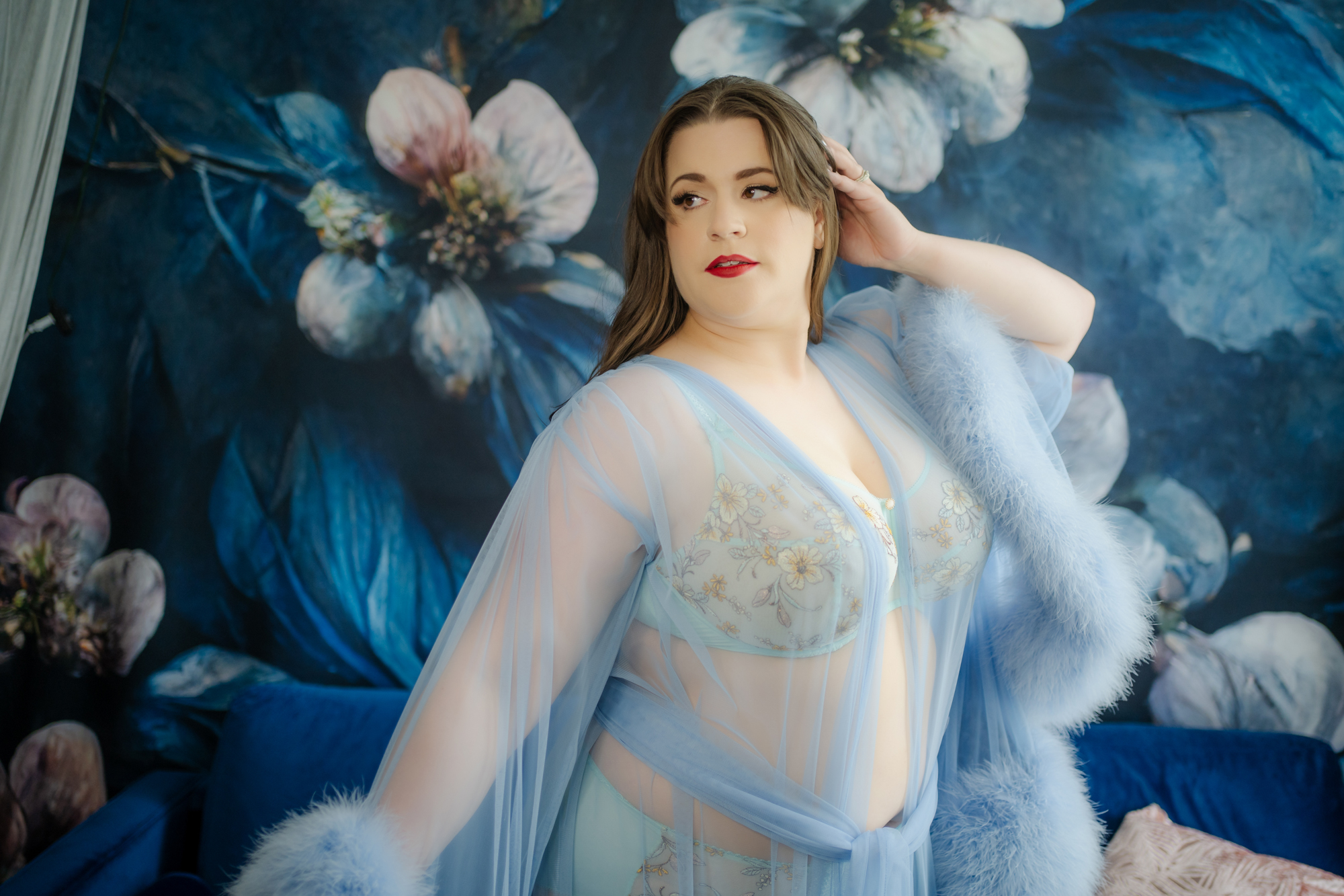 Beautiful curvy woman in blue lingerie and Catherine D'Lish luxury robe, at Georgian Bay Boudoir studios, against a blue floral backdrop